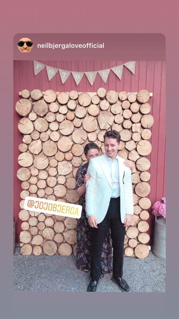 Woman hiding behind young man in front of wedding photo backdrop