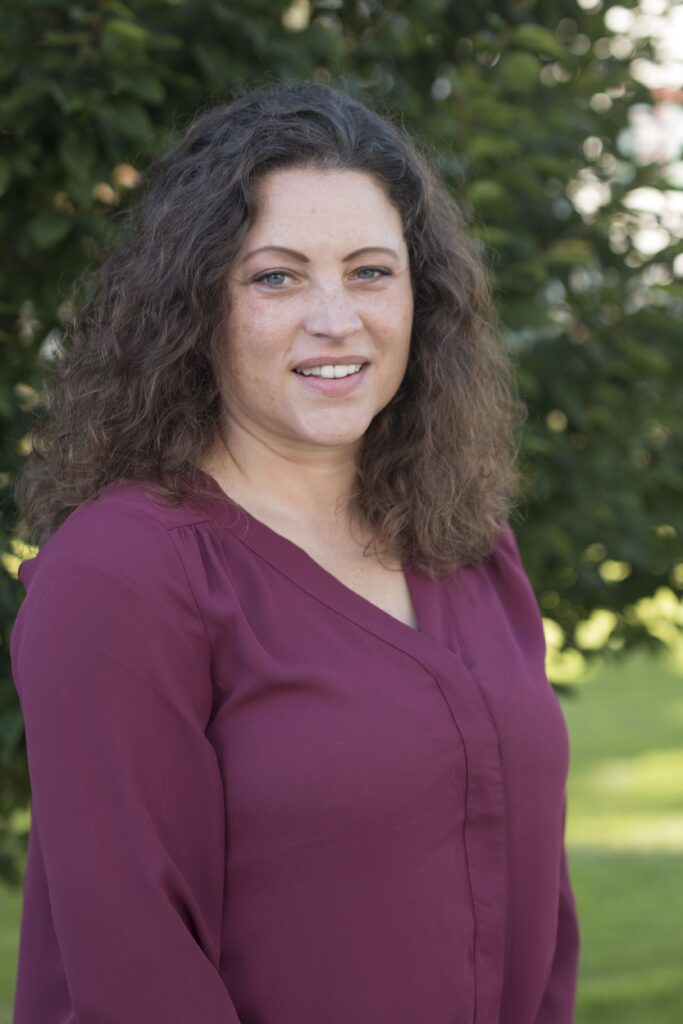 photo of woman in front of bush with dark hair and burgundy blouse