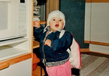 toddler standing next to microwave oven