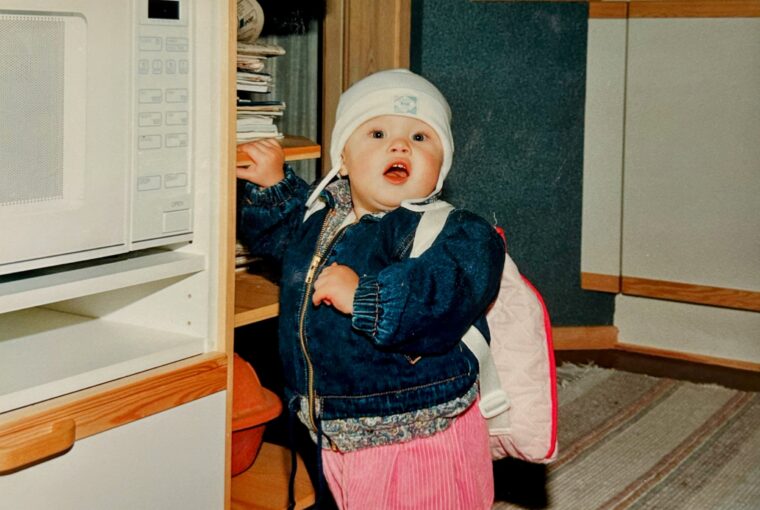 toddler standing next to microwave oven